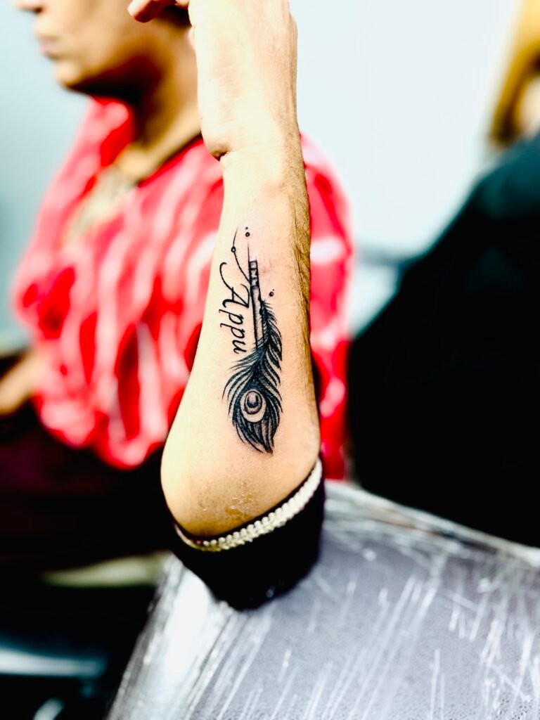 tattoo shop in hebbal -Peacock feather tattoo design symbolizing grace, spirituality, and beauty inked with vibrant colors and fine detailing.